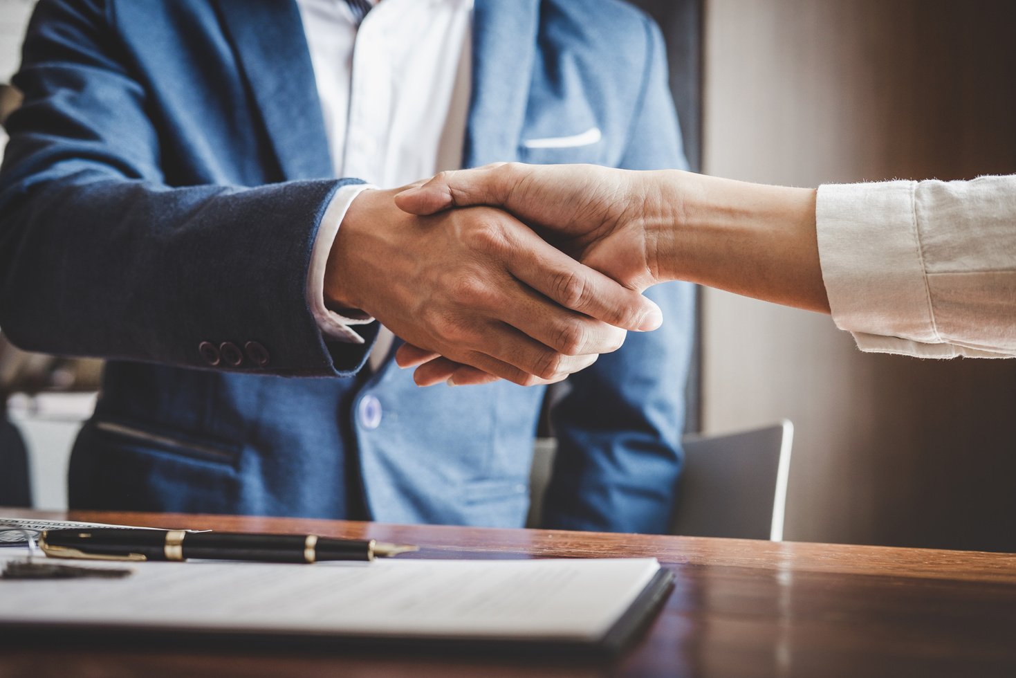 Real estate agent and customers shaking hands together celebrating finished contract after about home insurance and investment loan, handshake and successful deal